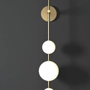 Sleek vertical wall light with three glowing spheres on a brass rod.