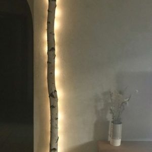 A tall tree adorned with lights stands in a cozy room, creating a warm and festive atmosphere.
